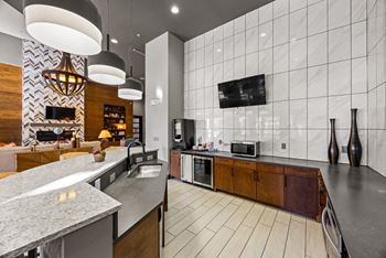 A modern kitchen with a marble countertop and a tv mounted on the wall.